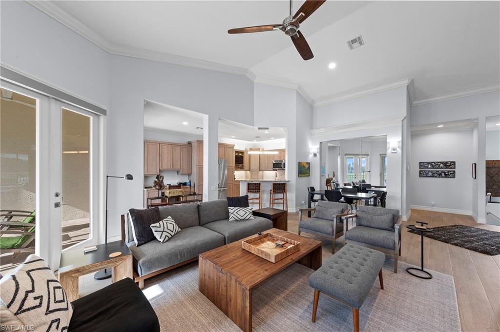 Open-concept living area featuring a wood-finish coffee table, gray upholstered seating, geometric area rug, and ceiling fan