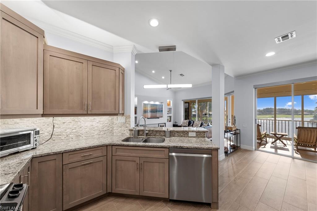 Kitchen with light wood-finish cabinetry, granite countertops, and a tile backsplash