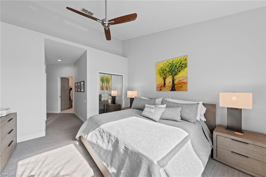 Spacious room featuring vaulted ceilings, a contemporary ceiling fan, and plush carpet flooring