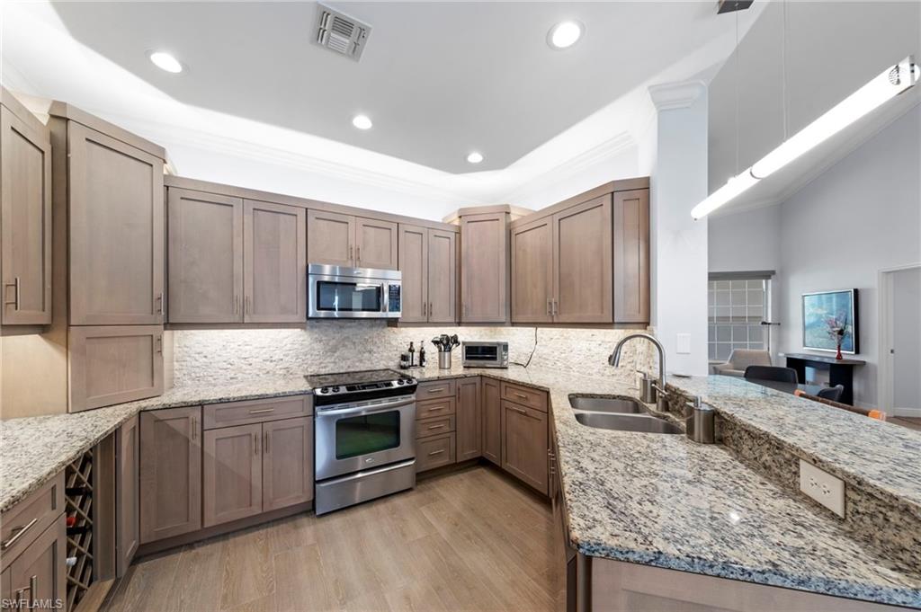 Contemporary kitchen featuring wood-finish cabinetry, granite countertops, a built-in stainless steel microwave, and a stainless steel range