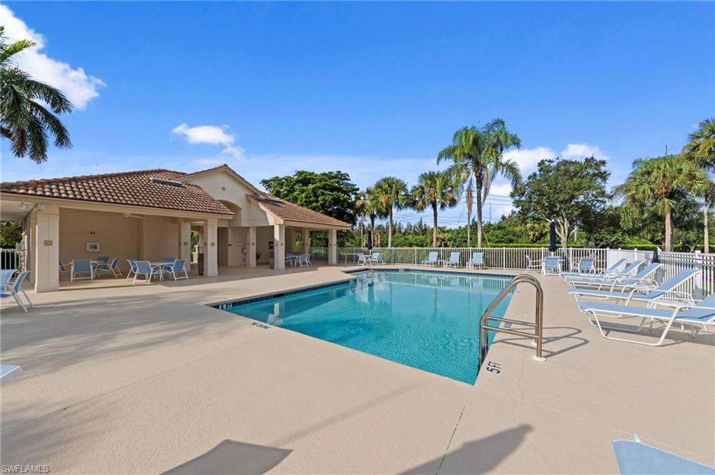 Outdoor swimming pool featuring a tanning ledge and perimeter fencing
