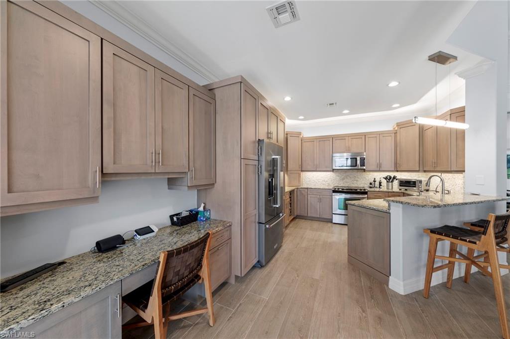 Spacious kitchen featuring custom wood cabinetry, granite countertops, stainless steel appliances, and a large island with seating