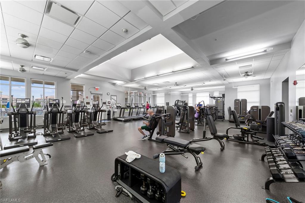 Spacious fitness center featuring a wide array of cardio and strength training equipment, rubberized flooring, ceiling fans, and large windows
