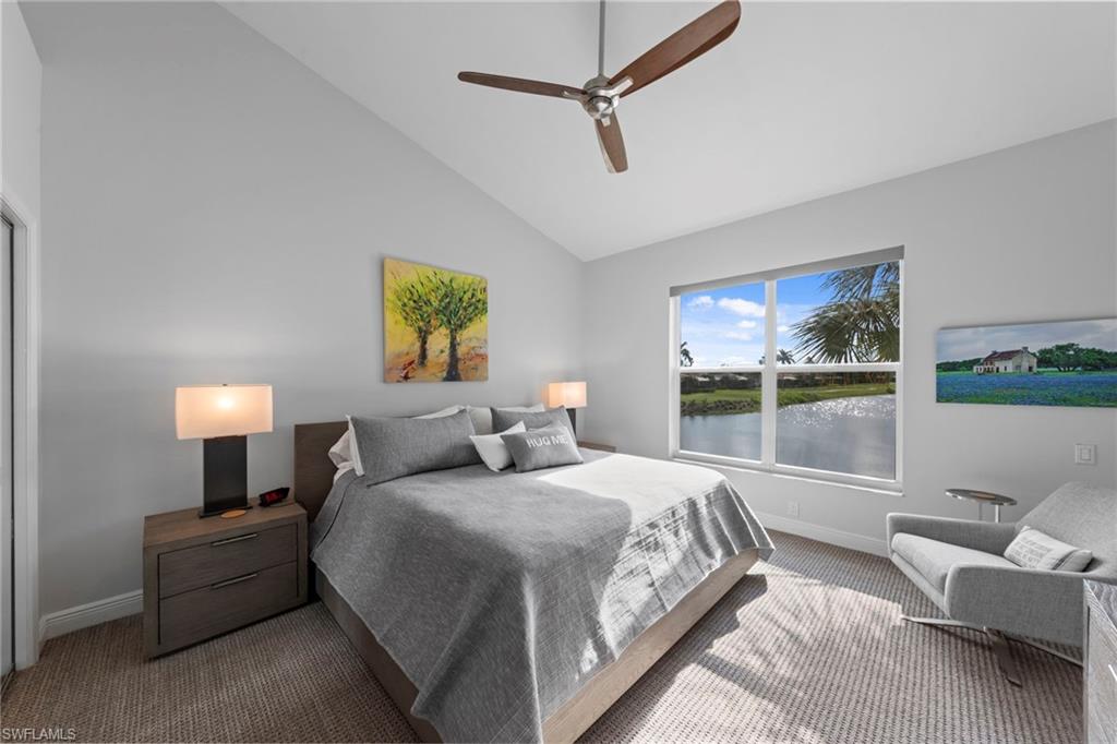 Vaulted ceiling bedroom with a contemporary ceiling fan, large window, and light-toned carpeting