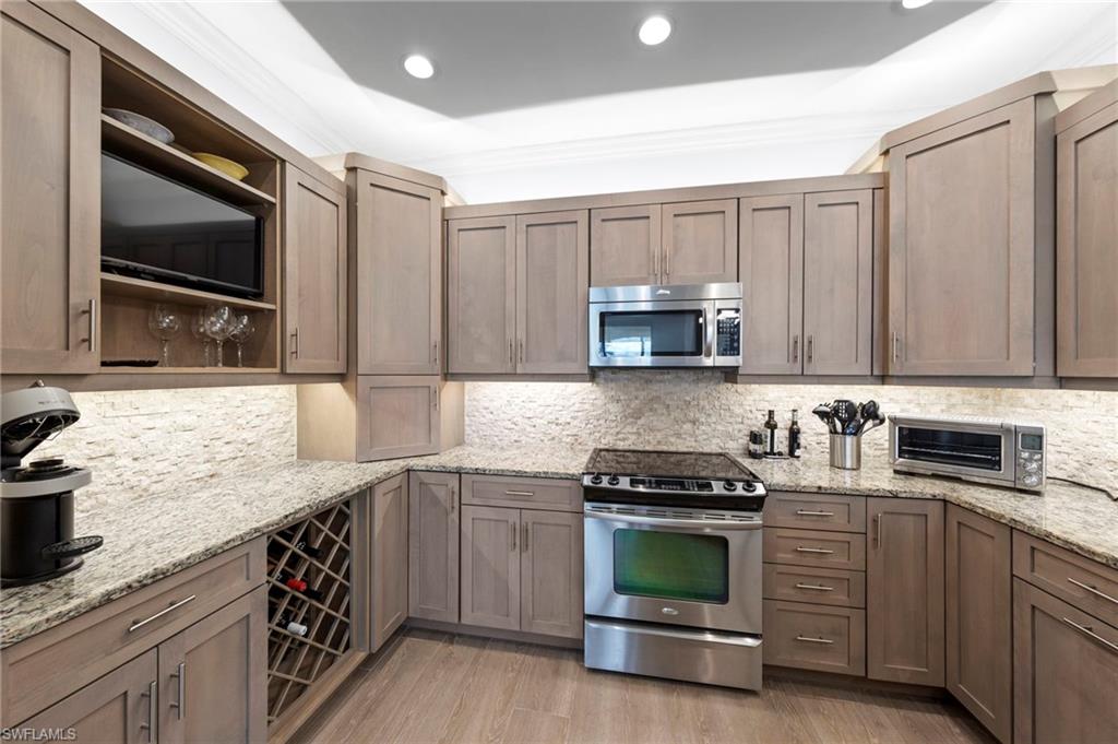 Sophisticated kitchen featuring custom cabinetry with recessed panel doors, granite countertops, and a coordinating tile backsplash