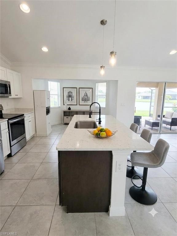Modern kitchen and dining area featuring a spacious island with waterfall-edge countertop, pendant lighting, and integrated seating