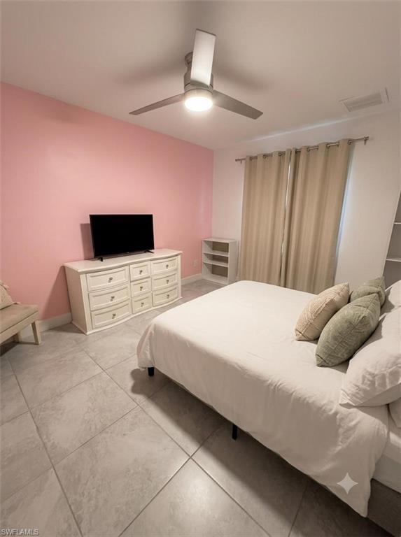 Bedroom featuring a modern ceiling fan with integrated lighting, tiled flooring, and a window with neutral drapes