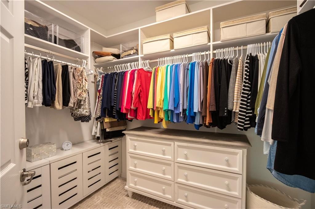 Custom walk-in closet featuring built-in shelving, multiple hanging rods, integrated drawer storage, and a central dresser with a light gray countertop
