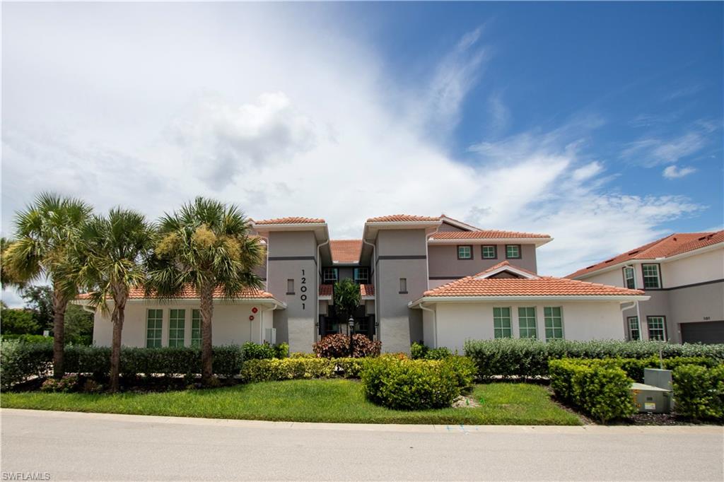 Multi-story structure featuring a terra cotta tile roof, stucco exterior, and palm trees