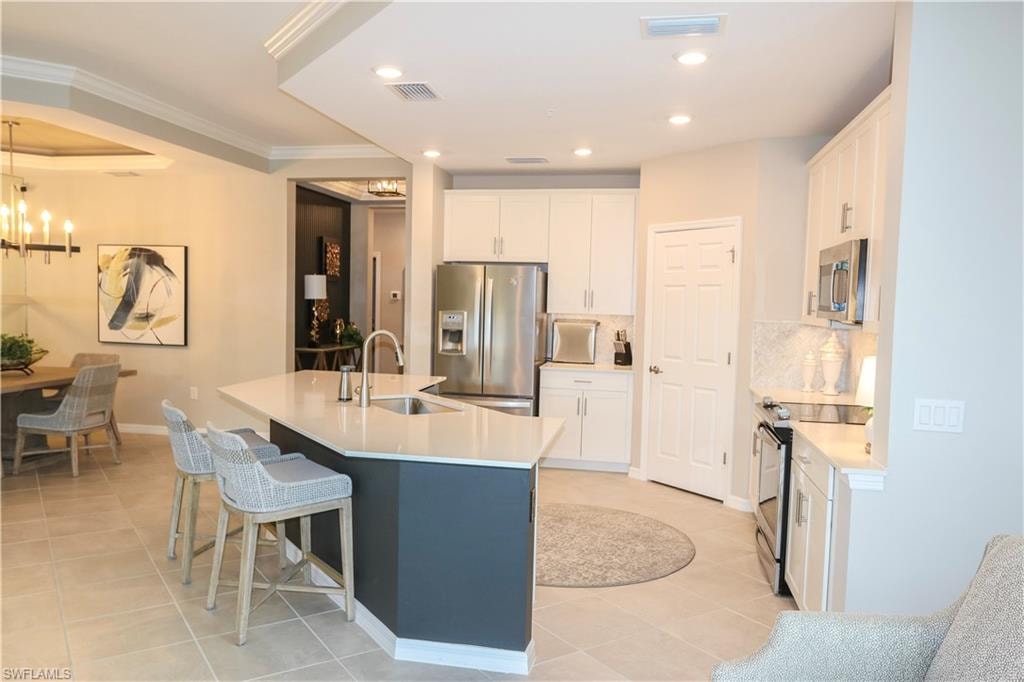 Kitchen island with a light-toned countertop, stainless steel sink, and gooseneck faucet