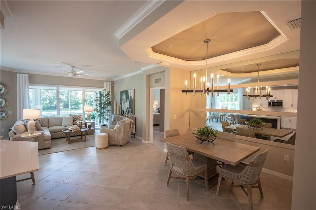 Open-concept living and dining areas featuring large format tile flooring and crown molding