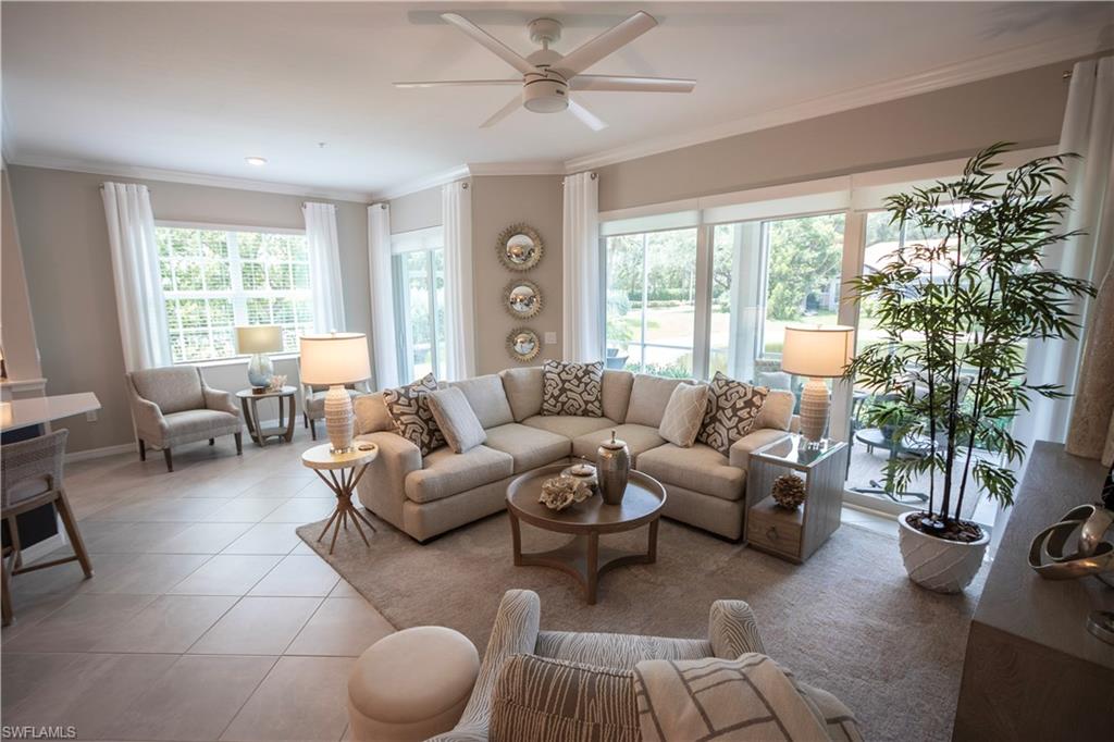 Spacious living area featuring large windows and glass sliding doors, light neutral wall tones, crown molding, and a ceiling fan