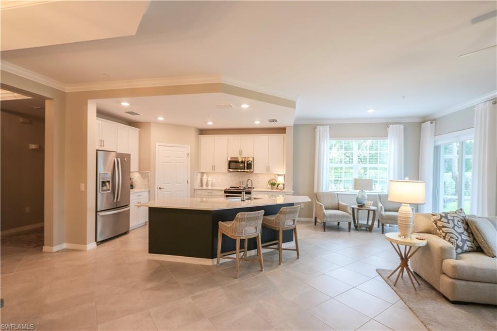 Open-concept design featuring tile flooring, a kitchen island with seating, stainless steel appliances, and recessed lighting