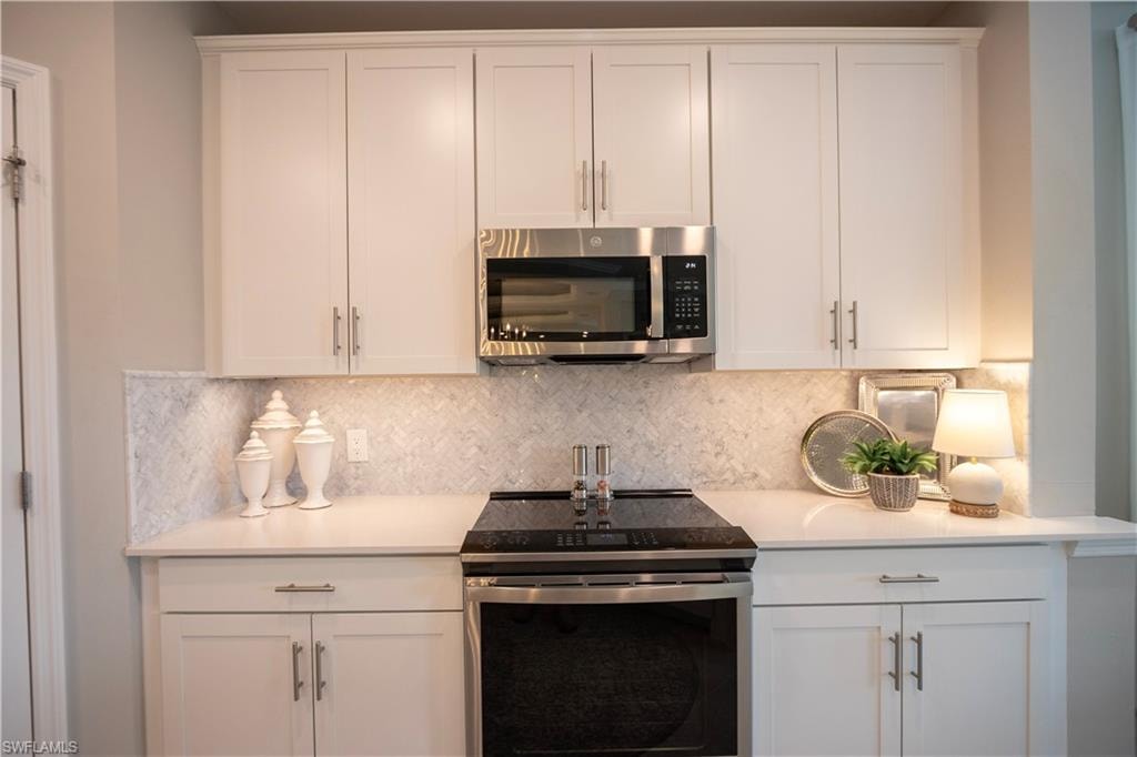 Sleek kitchen featuring white shaker-style cabinetry, a built-in stainless steel microwave, and an electric range