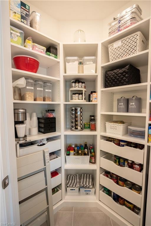Corner pantry featuring extensive adjustable shelving, multiple pull-out drawers, durable tile flooring, and integrated storage solutions