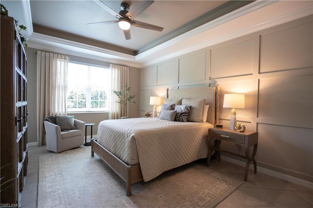 Sophisticated primary bedroom showcasing an upholstered wall-paneled accent wall, wood-frame bed with coordinating bedding, and dual nightstands with integrated lighting