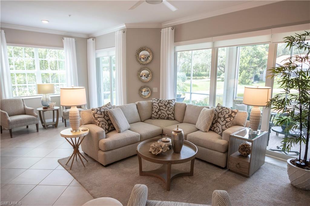Spacious living area featuring large windows, a ceiling fan, crown molding, and tiled flooring