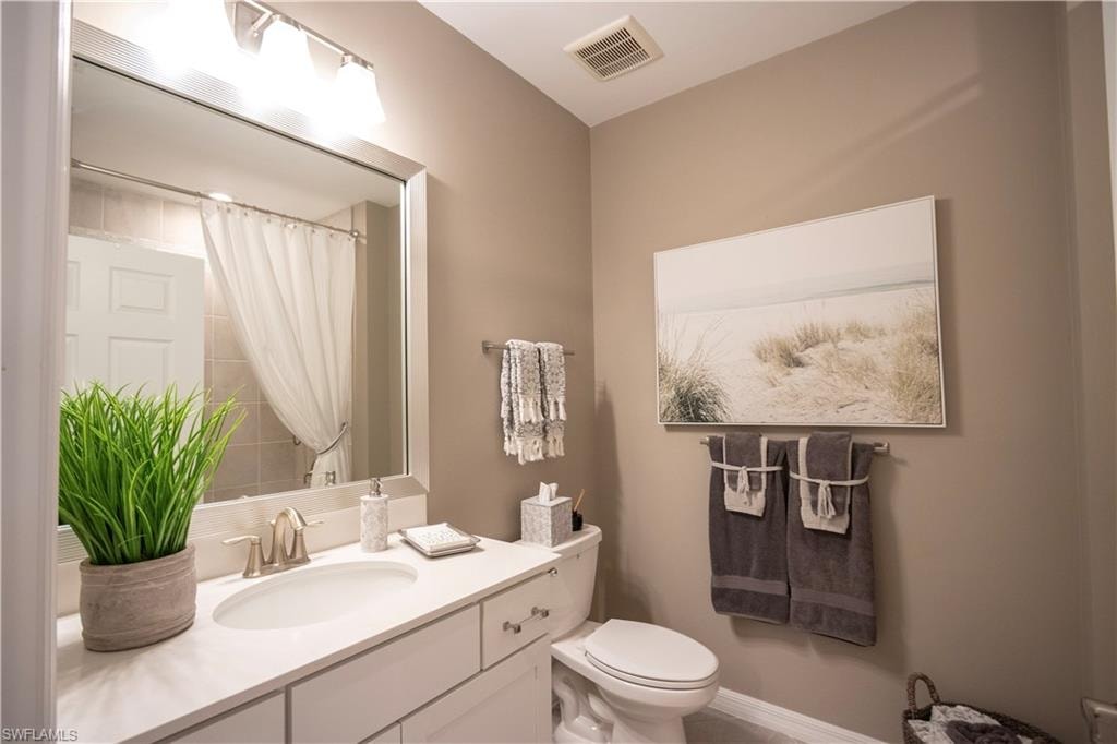 Bathroom featuring a single vanity with a white countertop, undermount sink, and brushed nickel faucet