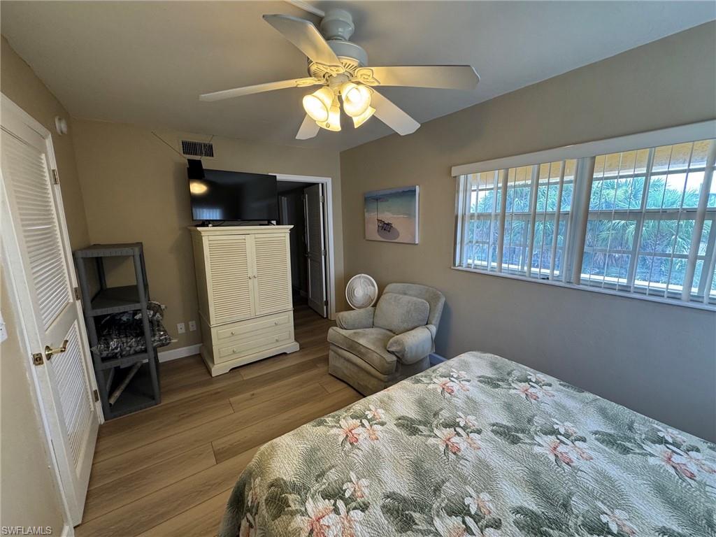 Bedroom featuring wood-finish tile flooring, a ceiling fan with integrated lighting, and louvered bifold closet doors