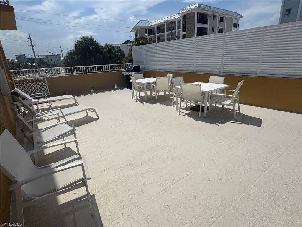 Expansive outdoor patio featuring light-toned large format tile flooring, a low privacy wall, and a slatted privacy fence