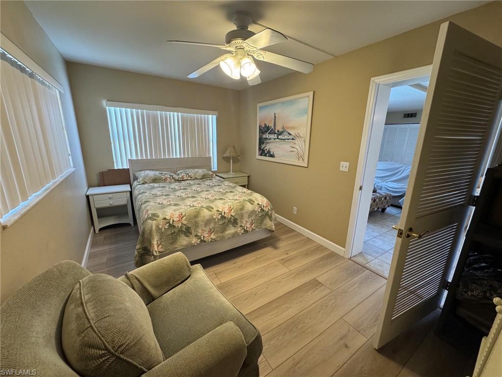 Bedroom featuring wood-finish tile flooring, a ceiling fan with integrated lighting, and louvered bi-fold doors