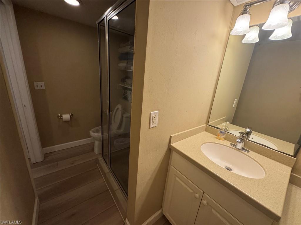 Bathroom featuring a single vanity with a countertop, an oval sink, and a mirrored wall