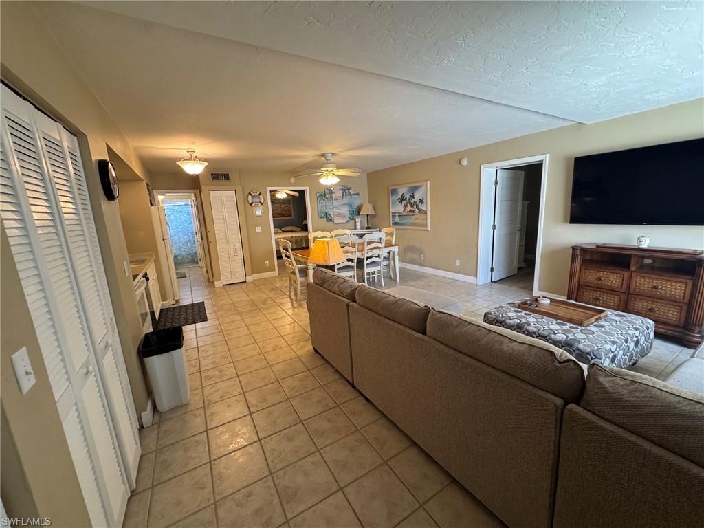 Expansive open-concept living space featuring neutral tile flooring, warm-toned walls, and recessed lighting