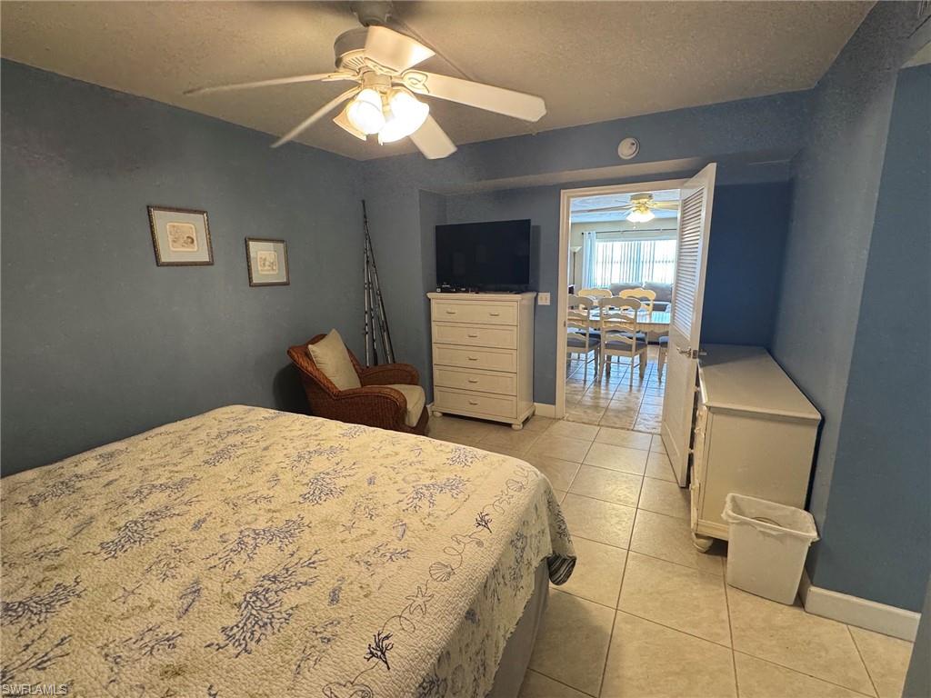 Room featuring a ceiling fan with integrated lighting, tiled flooring, and a doorway opening to an additional interior space