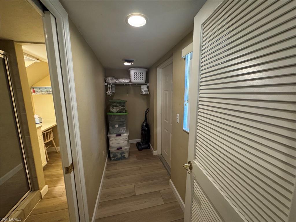 Hallway featuring wood-finish tile flooring, recessed lighting, and a built-in storage area with shelving