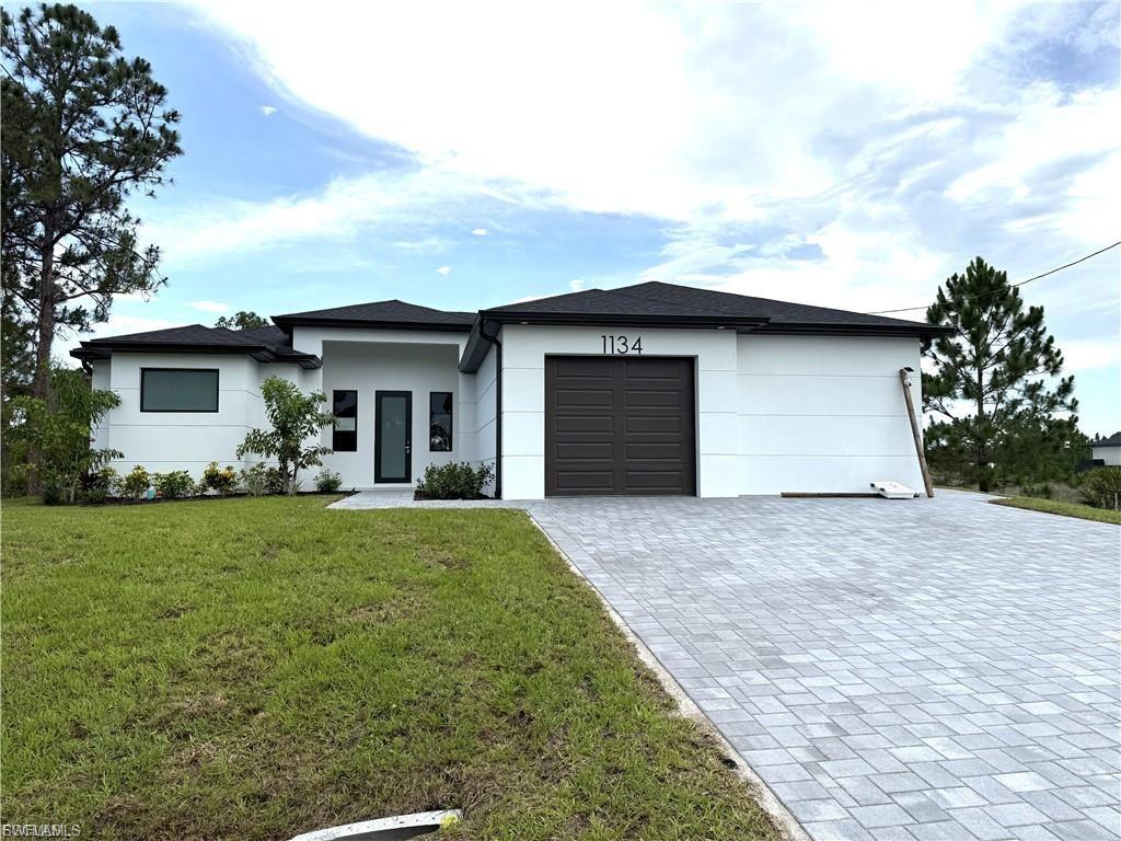 Contemporary single-story residence featuring a white stucco exterior, black-framed windows, and a black shingle roof