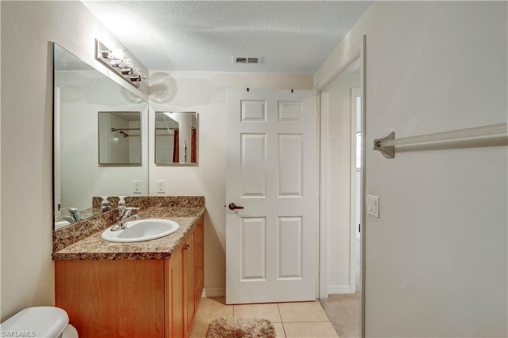 Elegant bathroom featuring warm wood-finish cabinetry with granite countertops, a round ceramic sink, and brushed nickel hardware