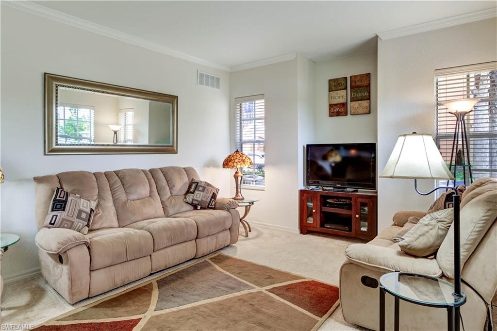 Bright and spacious living room showcasing a plush reclining sofa, entertainment center with wood-finish cabinetry, and large wall-mounted mirror that amplifies natural light
