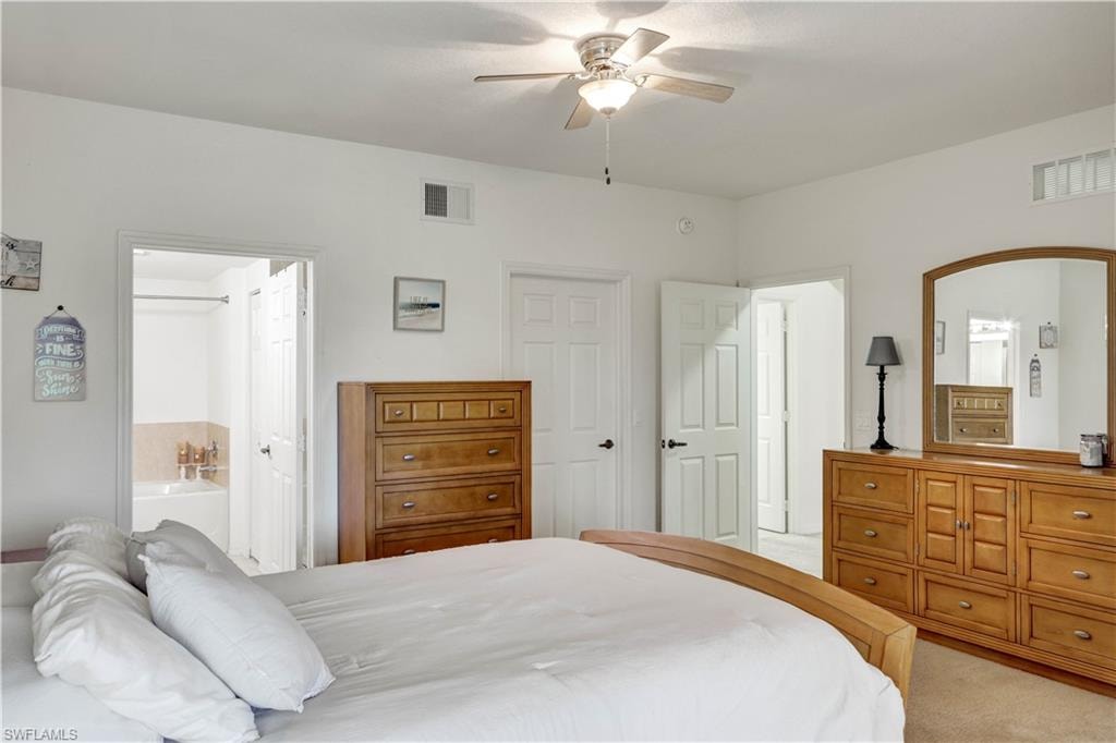 Carpeted bedroom featuring a ceiling fan with integrated lighting, white walls, and multiple doorways
