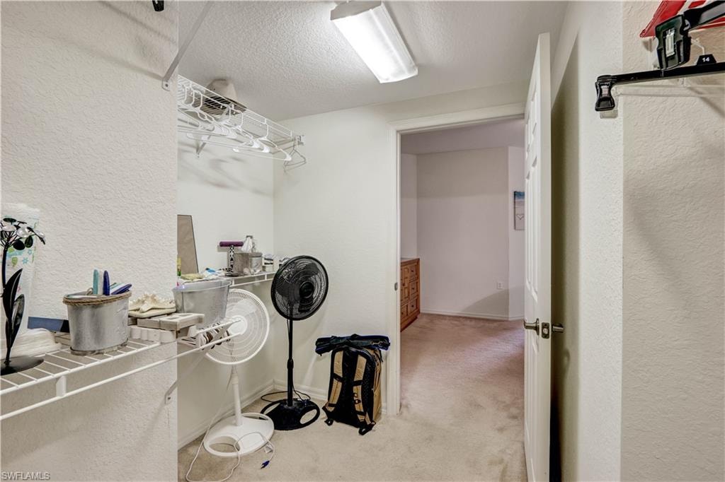Utility room featuring concrete flooring, white painted walls, fluorescent ceiling lighting, and ample storage space with wall-mounted shelving and organizational systems