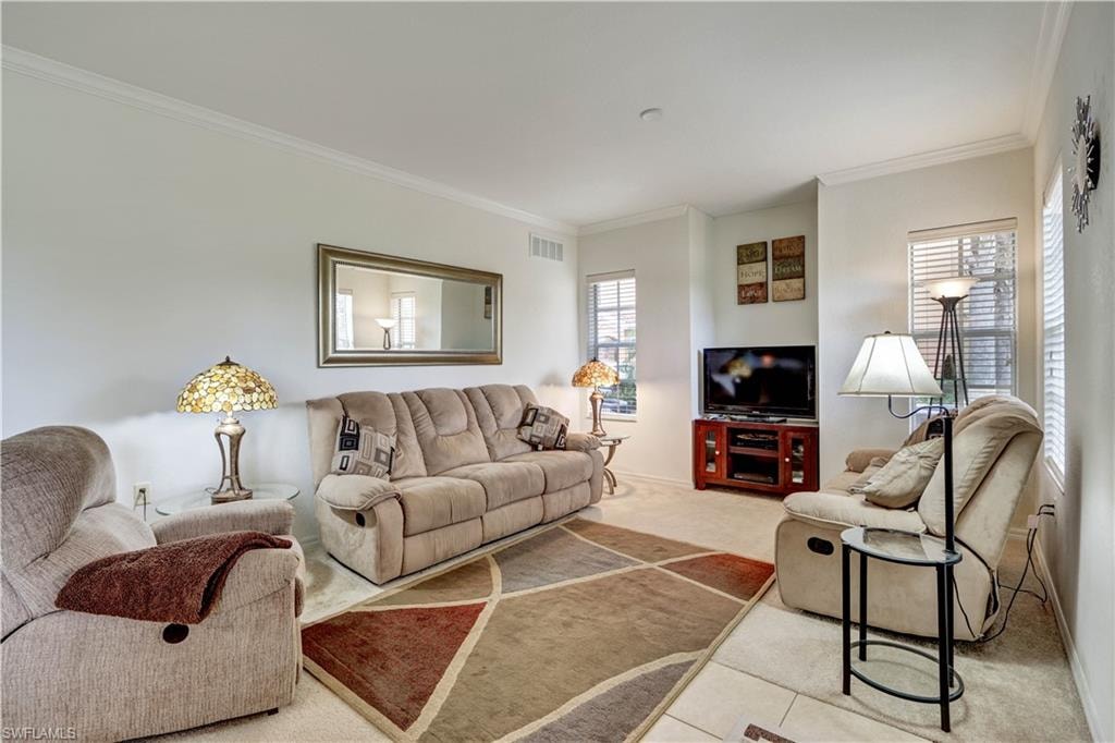 Spacious living area featuring light-toned wall finishes and crown molding