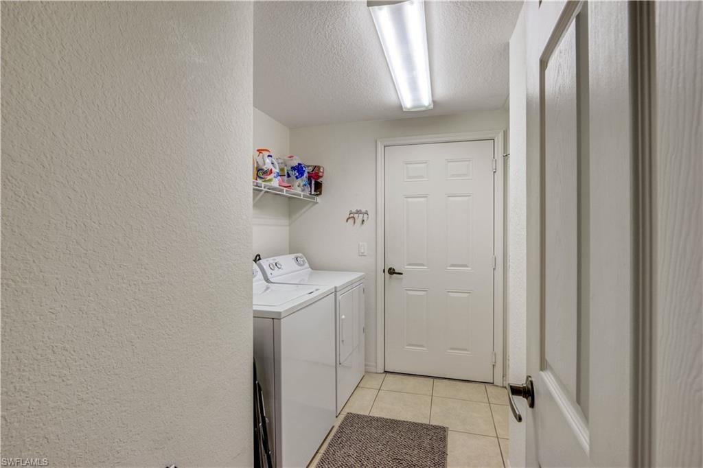 Dedicated laundry room featuring a front-load washer, ample cabinetry with countertop workspace, tile flooring, recessed lighting, and direct access to the home's interior