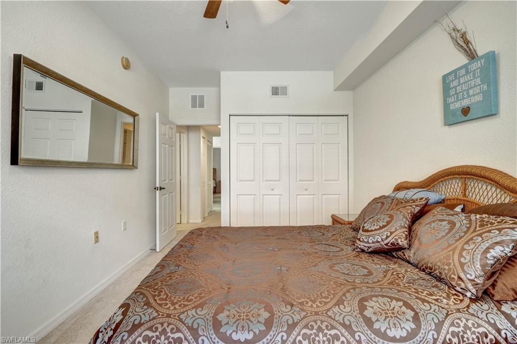 Spacious bedroom with wood-framed bed, patterned bedding, and multiple storage options including a large closet with six-panel doors