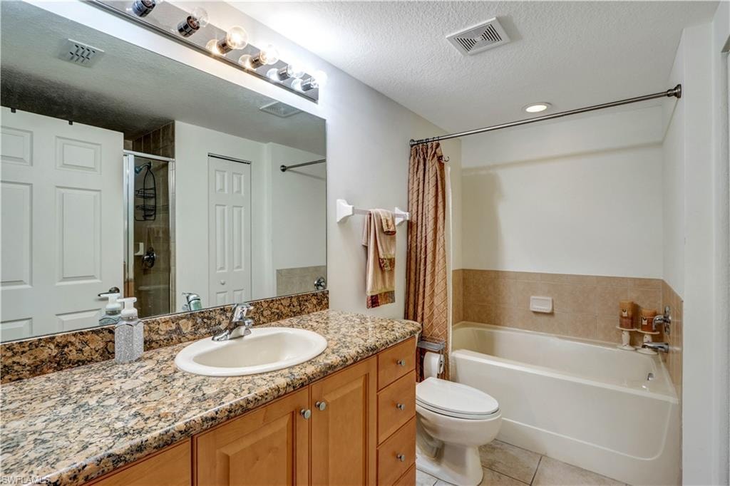 Spa-inspired master bathroom featuring dual-sink vanity with wood cabinetry and speckled granite countertops, frameless mirror with integrated lighting, and a separate soaking tub with tile surround and coordinating shower enclosure