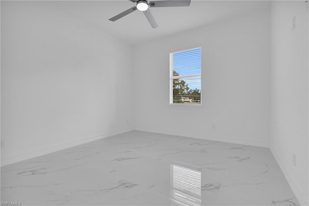 Empty room featuring light marble finish floors and ceiling fan