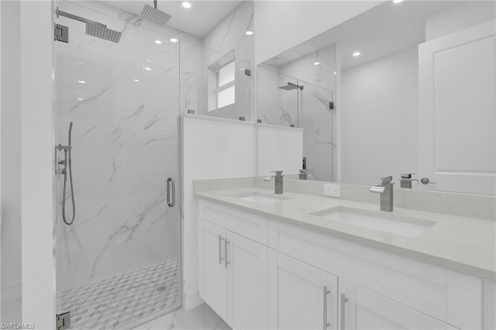 Full bathroom featuring a marble finish shower, double vanity, recessed lighting, and light marble finish floors