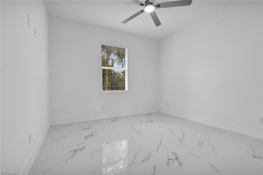 Spare room with marble look tile flooring and ceiling fan