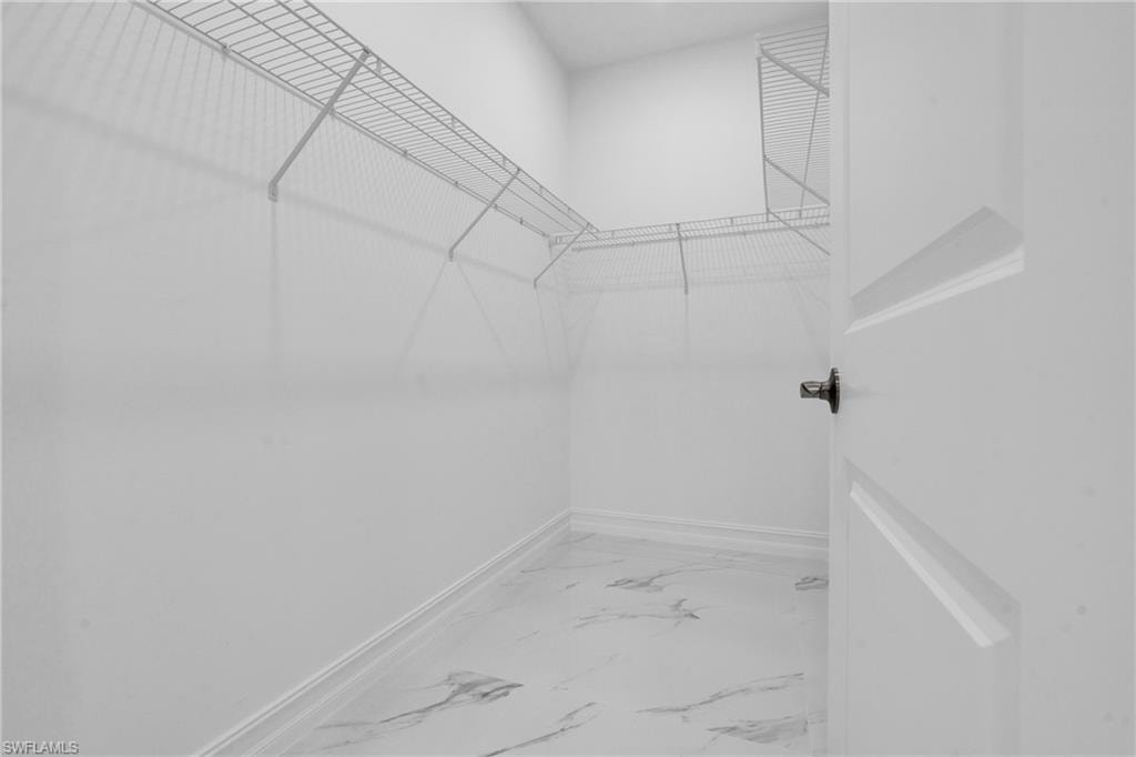 Spacious closet featuring light marble finish floors