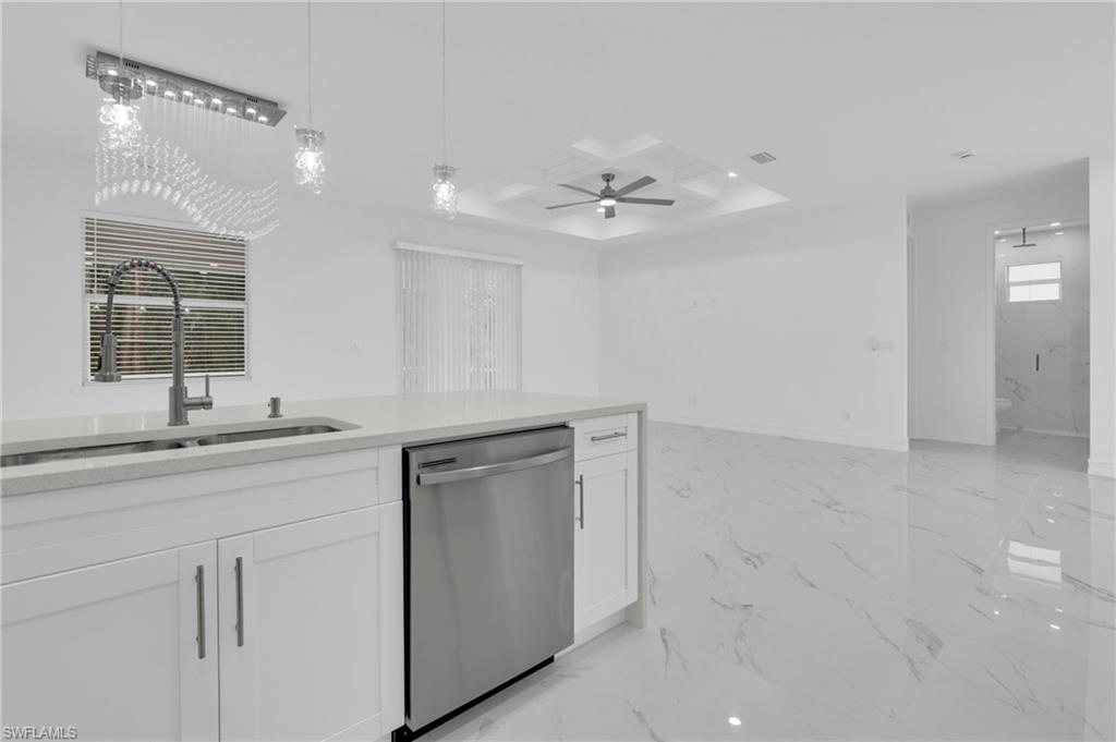 Kitchen featuring light stone countertops, dishwasher, light marble finish flooring, white cabinets, and coffered ceiling