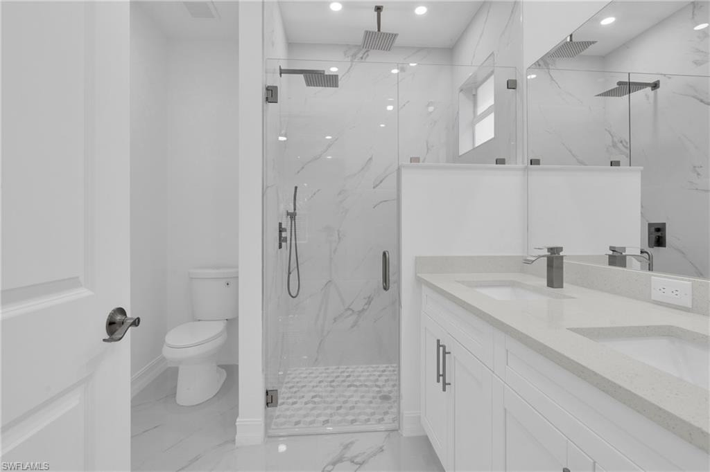 Full bathroom featuring light marble finish floors, double vanity, a marble finish shower, and recessed lighting