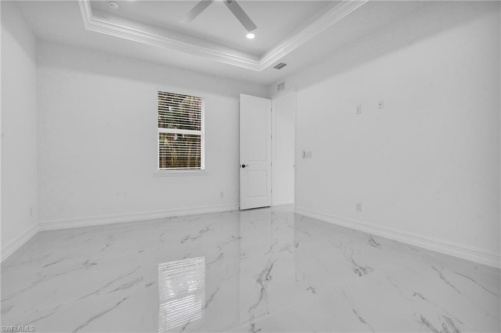 Spare room with light marble finish flooring, crown molding, recessed lighting, a raised ceiling, and a ceiling fan