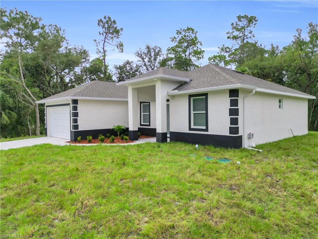 View of front of property featuring an attached garage, stucco siding, a front lawn, and concrete driveway