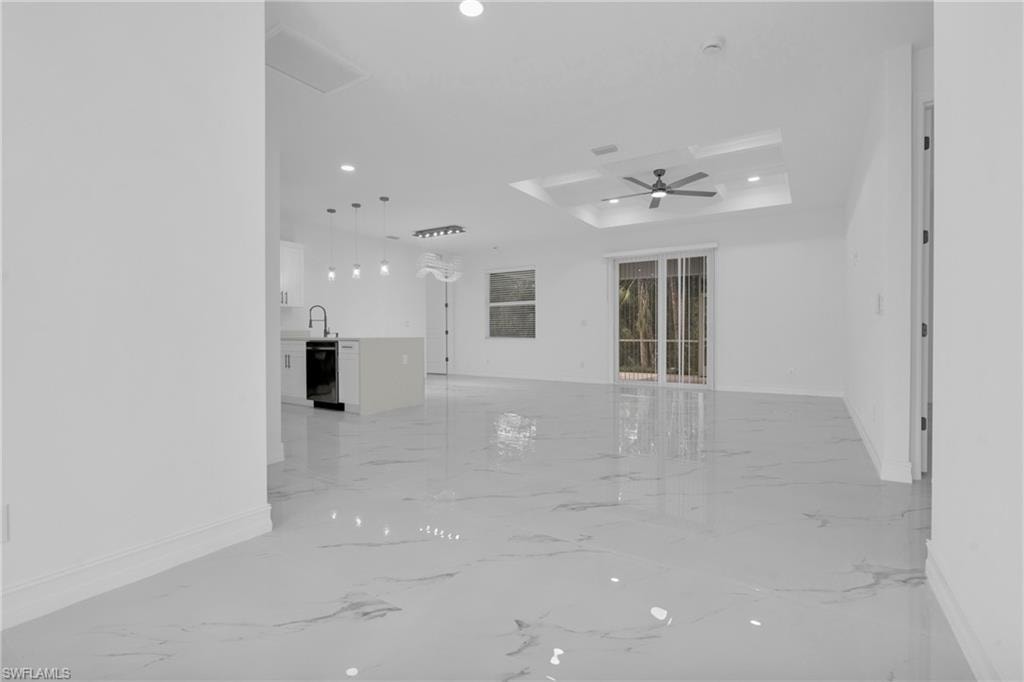 Unfurnished living room featuring a raised ceiling, recessed lighting, light marble finish flooring, and a ceiling fan