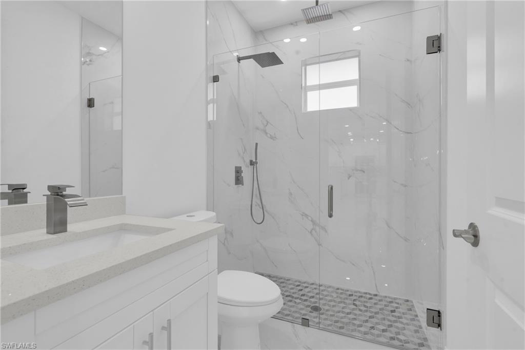 Bathroom with vanity, a marble finish shower, and marble finish floors
