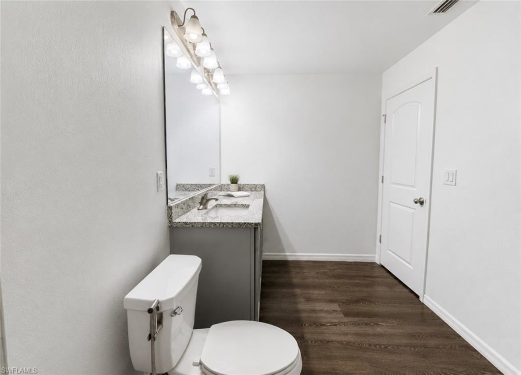 Wood-finish flooring, white walls, and a white interior door with a curved arch detail