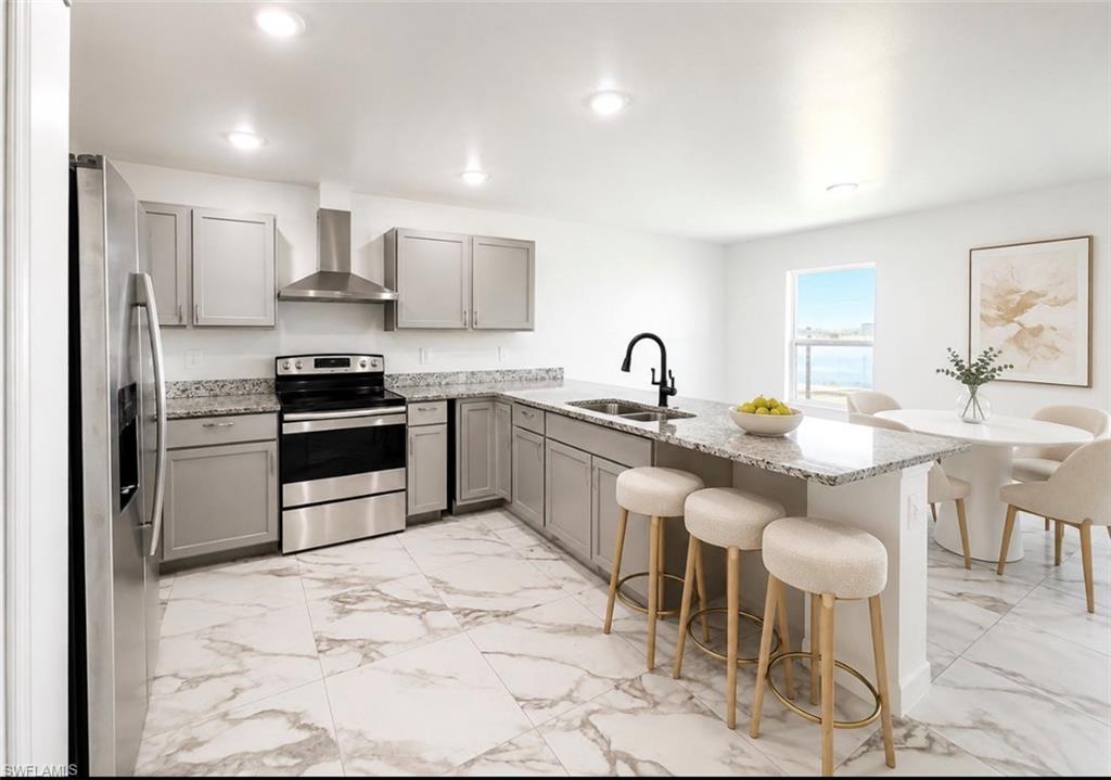 Kitchen featuring stainless steel appliances, light gray cabinetry, granite countertops, an island with a sink, and large format marble-look tile flooring